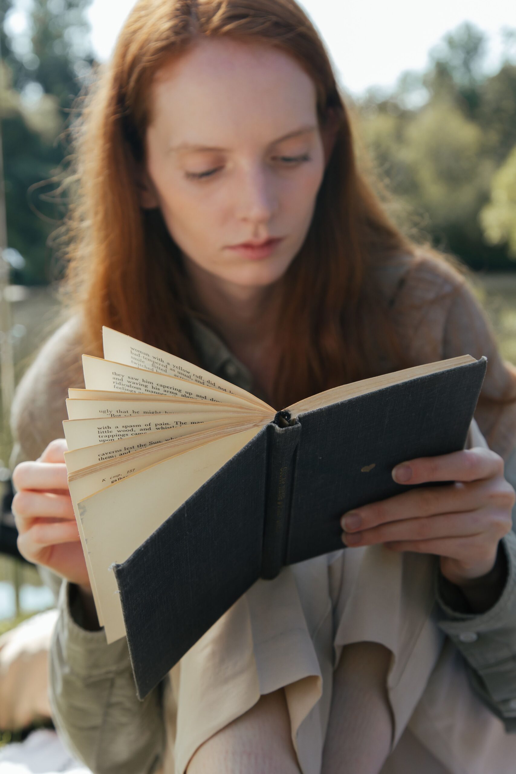 mujer relajandose en el parque mientras lee un libro
